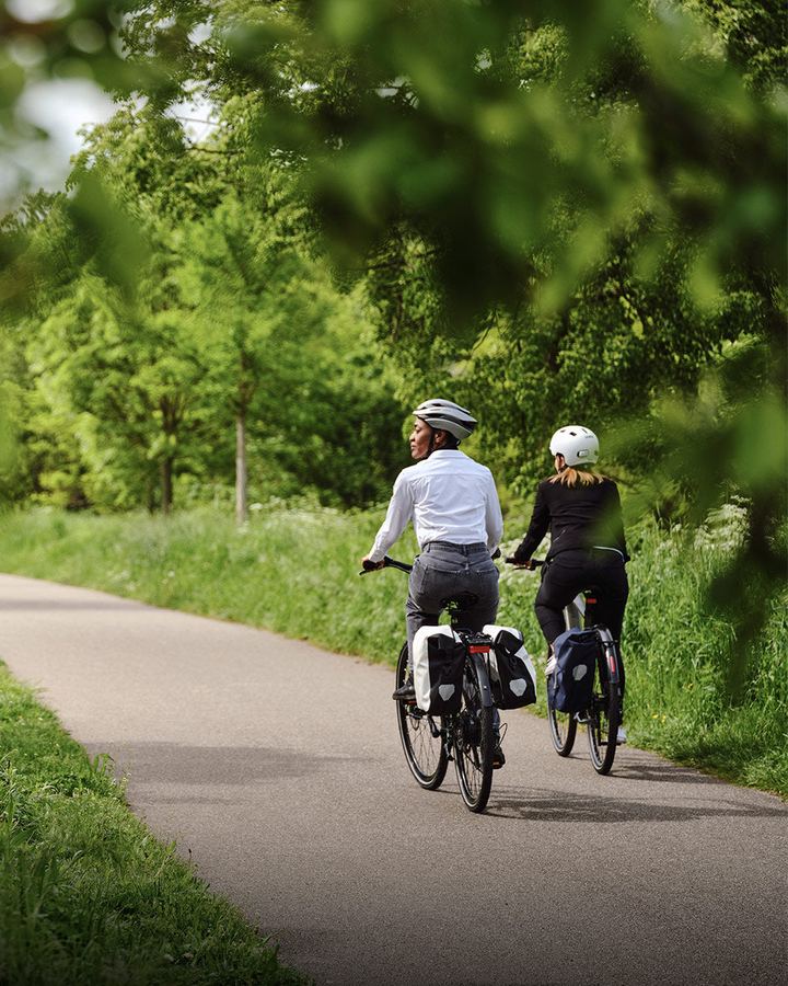 Zwei Radfahrerinnen mit Packtaschen auf einem Radweg im Grünen