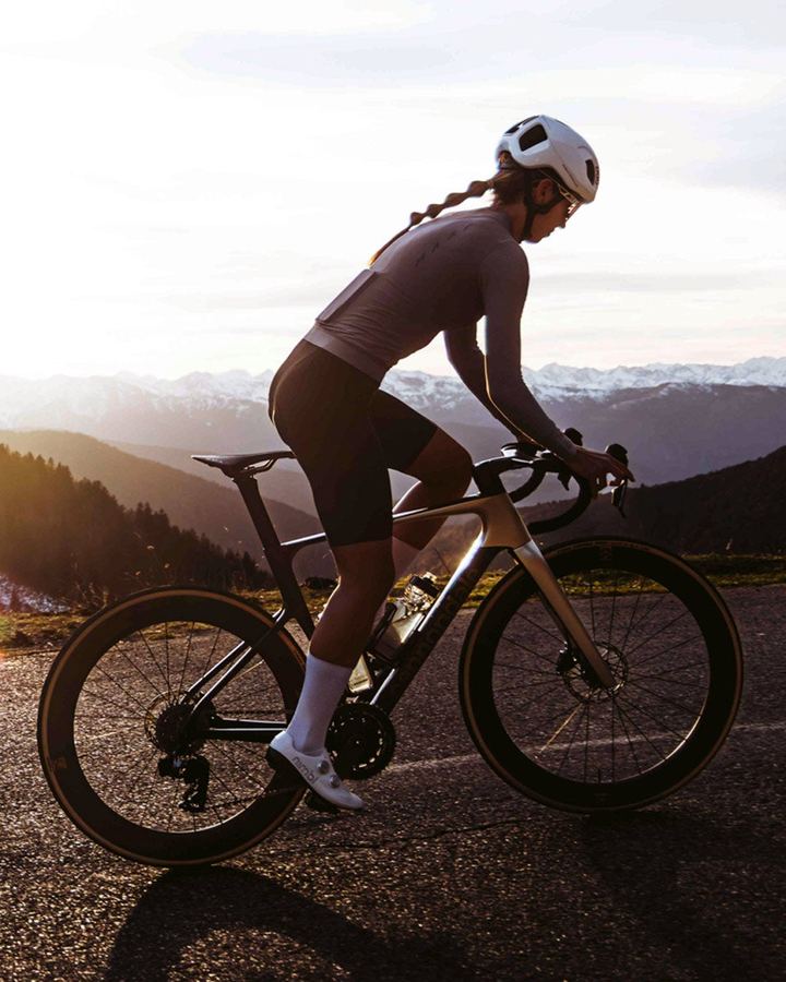 Rennradfahrerin im Gegenlicht auf einer Bergstraße