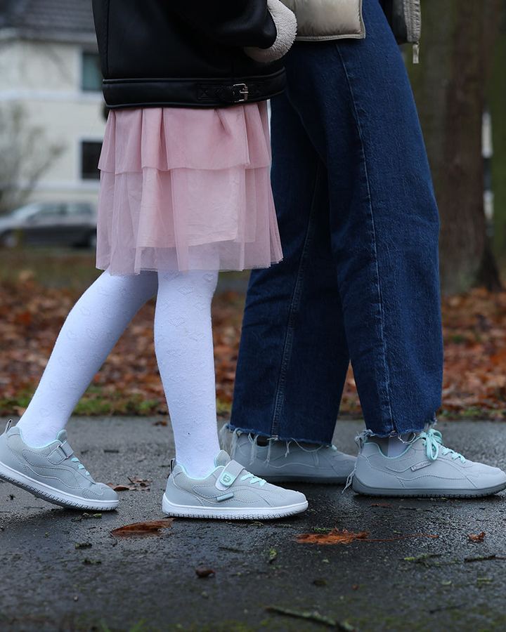 Kind und Erwachsener laufen in Freiluftkind-Barfußschuhen über einen herbstlichen Weg