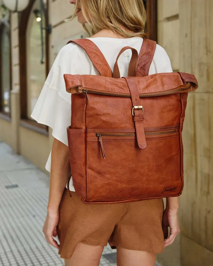 Back view of a woman with a cognac leather backpack in an old-town lane