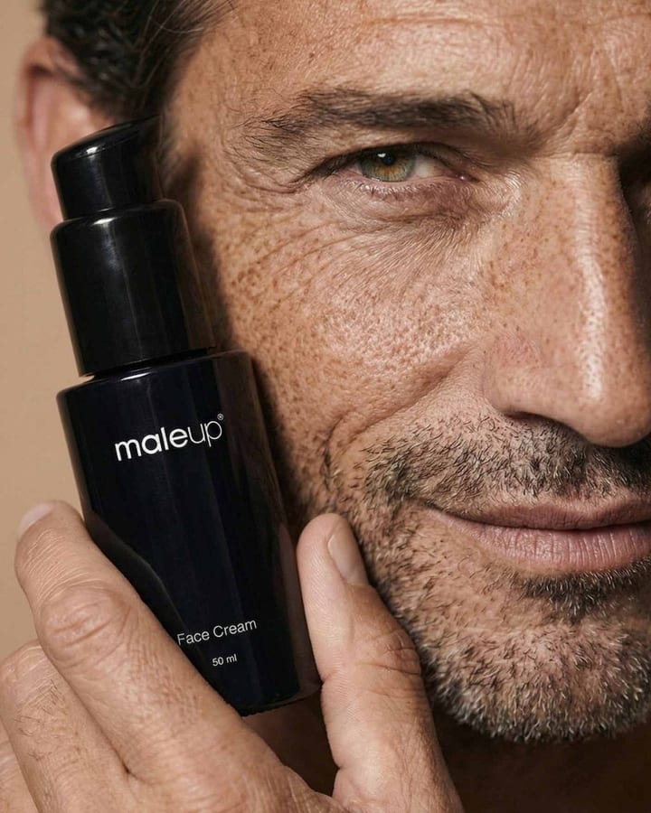 Mann mit Dreitagebart hält einen schwarzen maleup-Spender mit Face Cream an die Wange