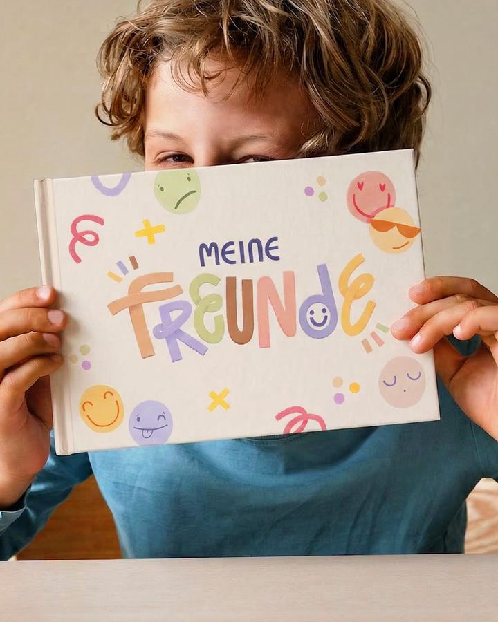 Junge hält sein Mintkind-Freundebuch vor das Gesicht