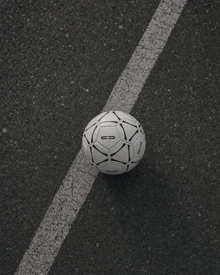 White football with black lines lying on a white marking on dark asphalt