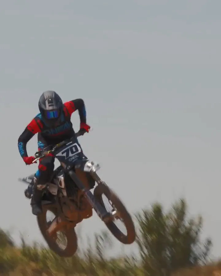 Motocross rider in an O'Neal goggle and helmet, then airborne over a crest