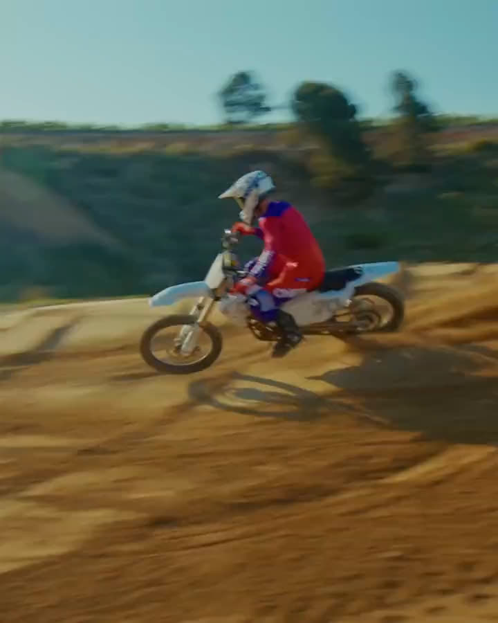 Motocross-Fahrer im rot-violetten O'Neal-Jersey auf einer Kuppe und in einer staubigen Kurve