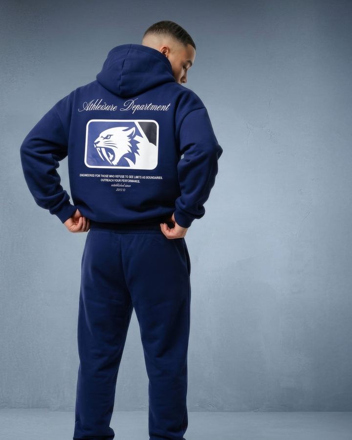 Man seen from behind in a navy hoodie with back print against a blue-grey backdrop