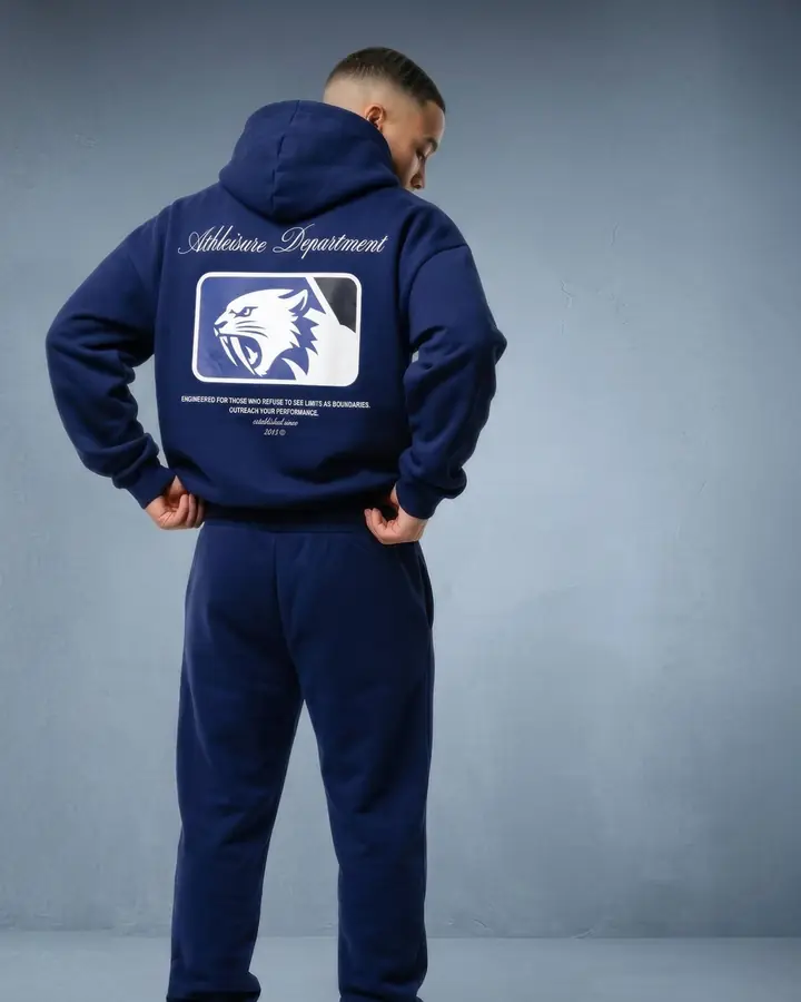 Mann von hinten in dunkelblauem Hoodie mit Rückenprint vor blaugrauem Hintergrund