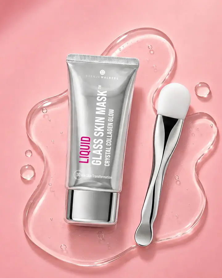 Tube Liquid Glass Skin Mask mit Silberspatel auf einer klaren Gel-Pfütze vor rosa Hintergrund.